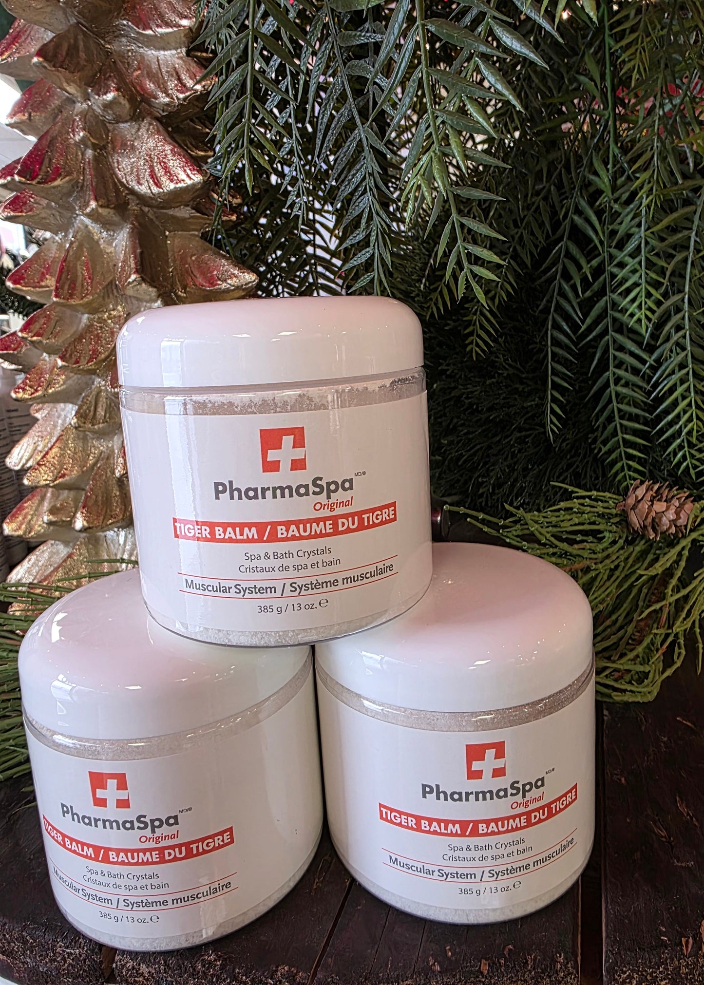 Three containers of Pharmaspa product on a wooden surface with greenery in the background