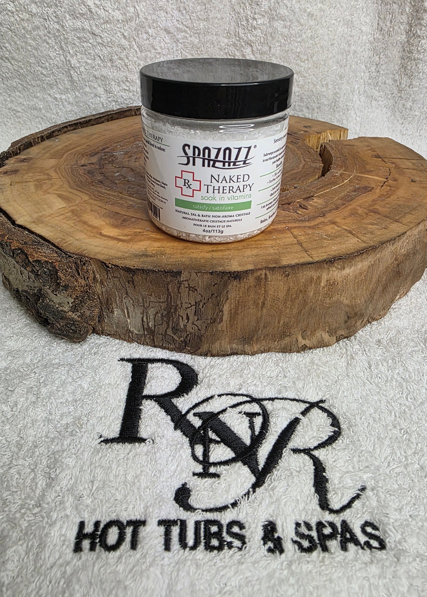 Small bottle of Spazazz Naked Therapy aromatherapy crystals on a wooden block with RnR Hot Tubs & Spas branding in the background.