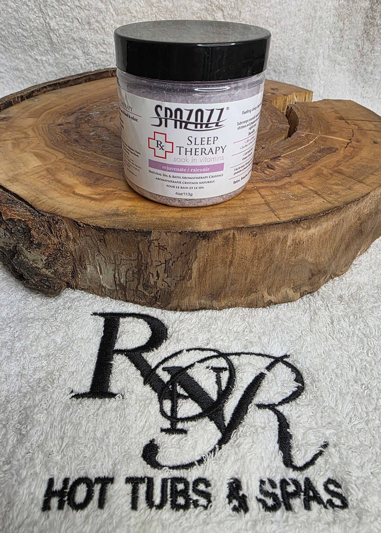 Jar of Spazazz Sleep aromatherapy crystals on a wooden block with RnR Hot Tubs & Spas branding in the background.
