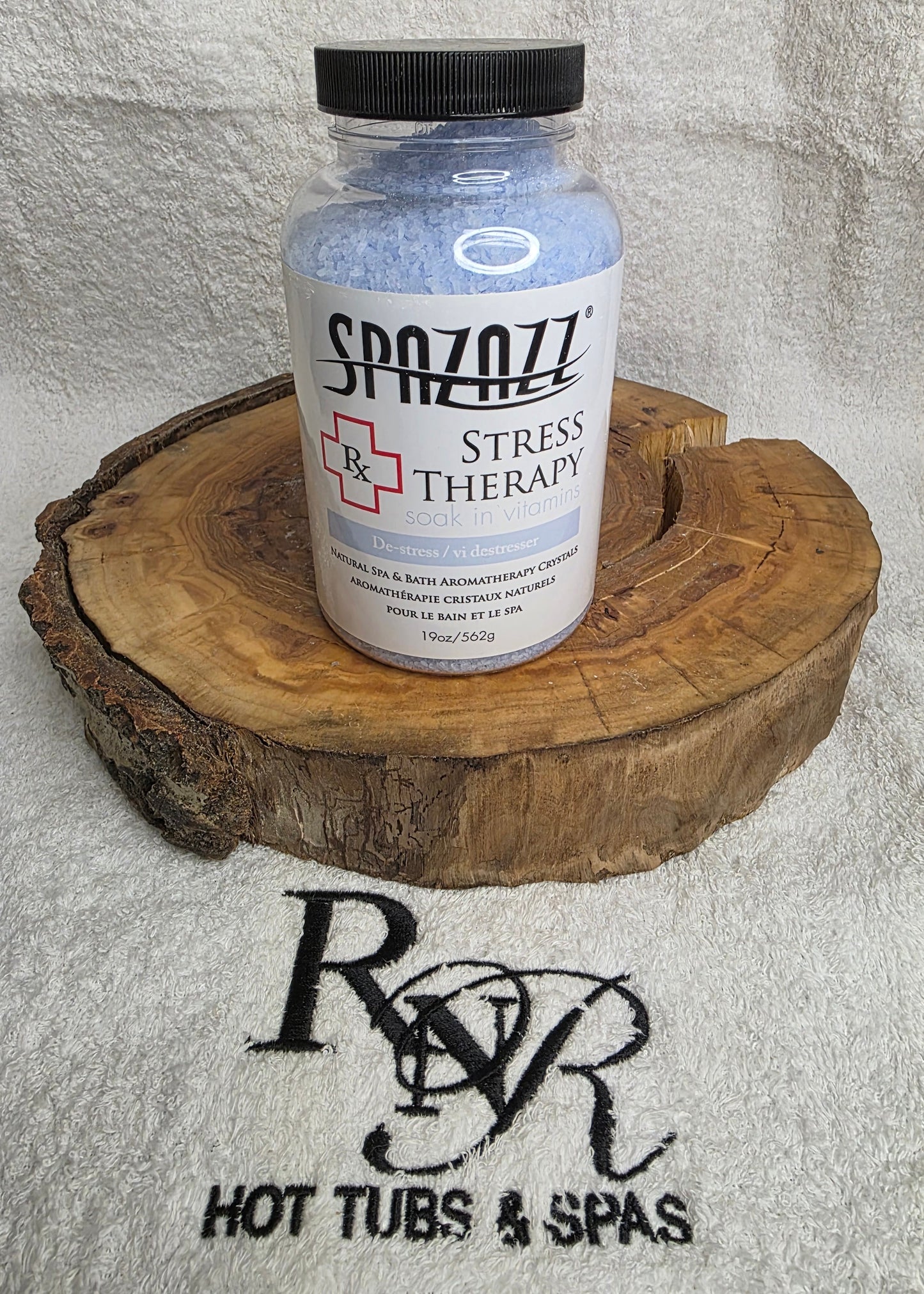 Bottle of Spazazz Stress Therapy on a wooden block with RnR Hot Tubs & Spas logo in the background.