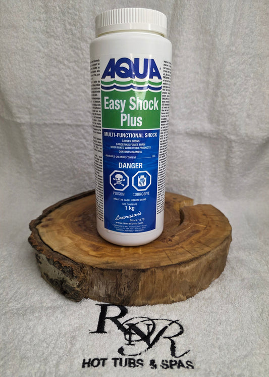 Aqua Easy Shock Plus pool chemical bottle on a wooden block with a towel and RnR Hot Tubs & Spas logo in the background.
