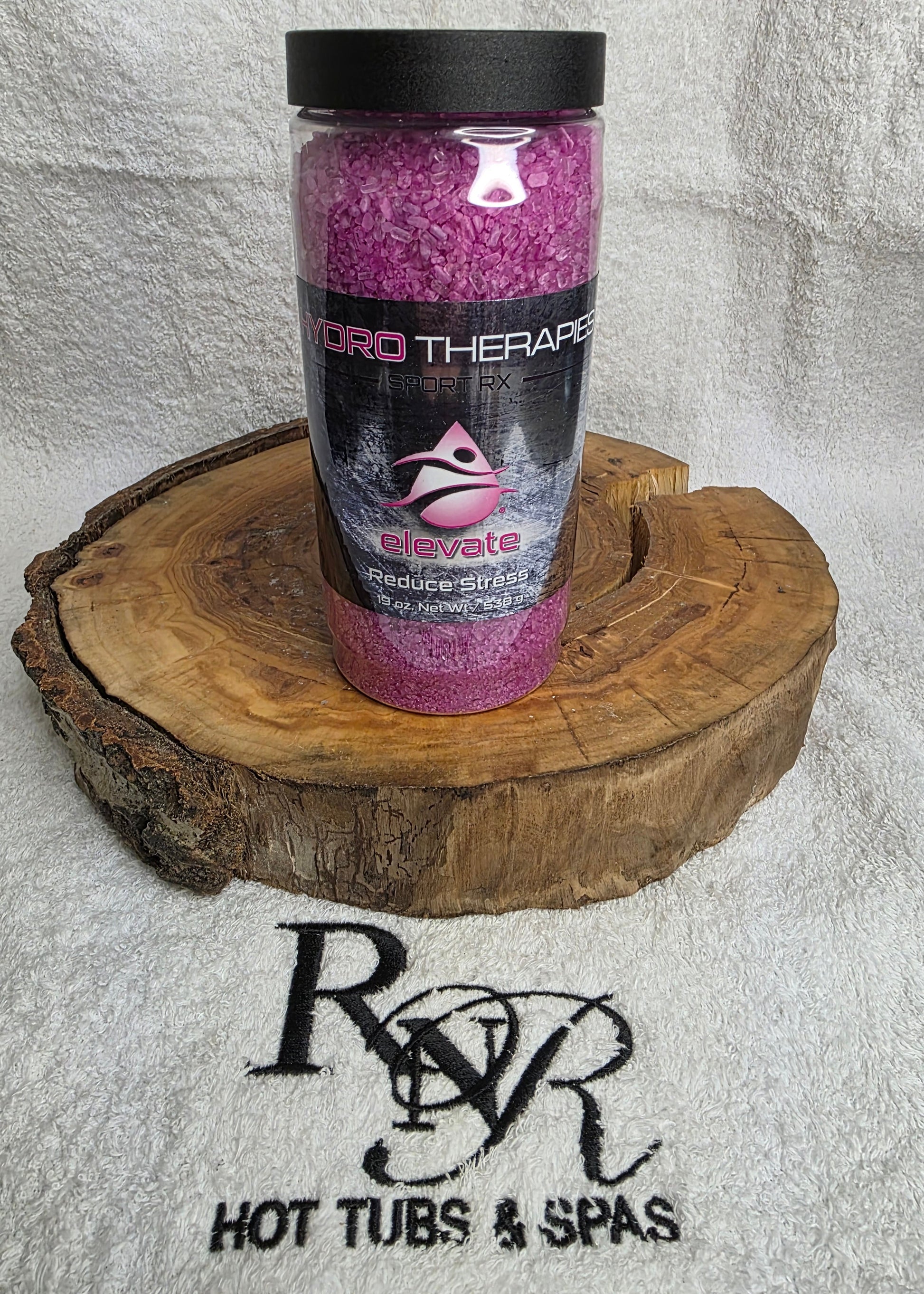 Bottle of Hydro Therapies Elevate aromatherapy crystals on a wooden block against a branded background