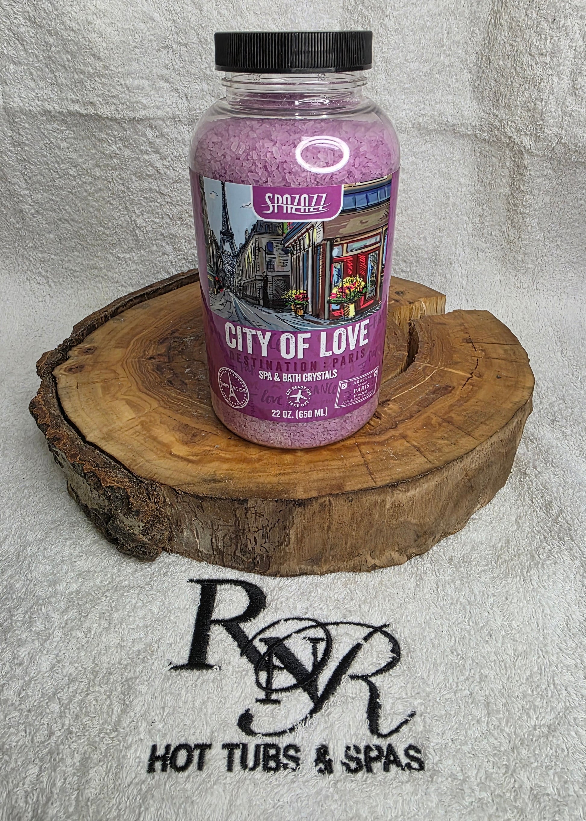 Bottle Spazazz Destination City of Love aromatherapy crystals on a wooden block with RnR Hot Tubs & Spas branding in the background.