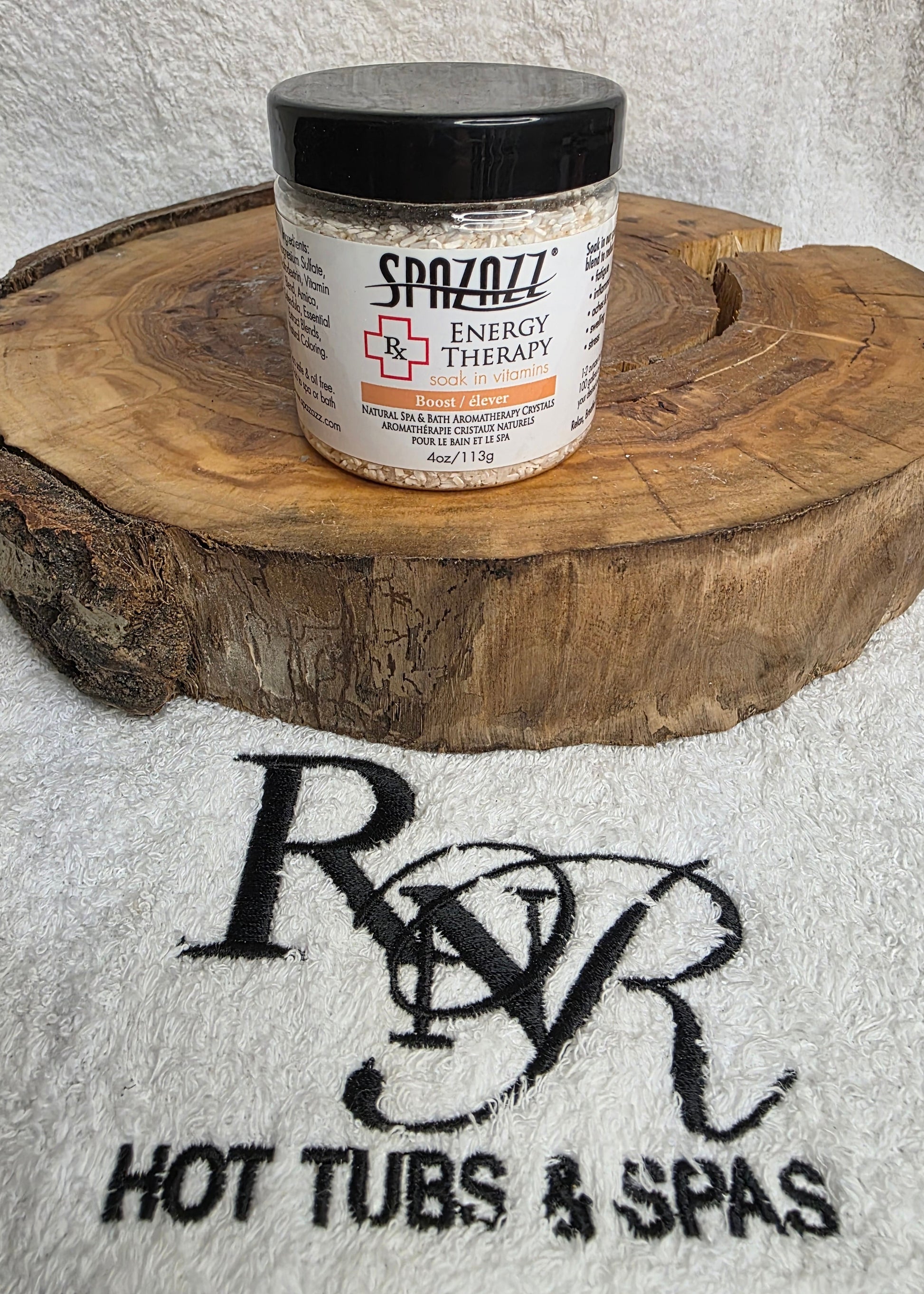 Container of Spazazz Energy aromatherapy crystals on a wooden block with RnR Hot Tubs & Spas logo in the background.