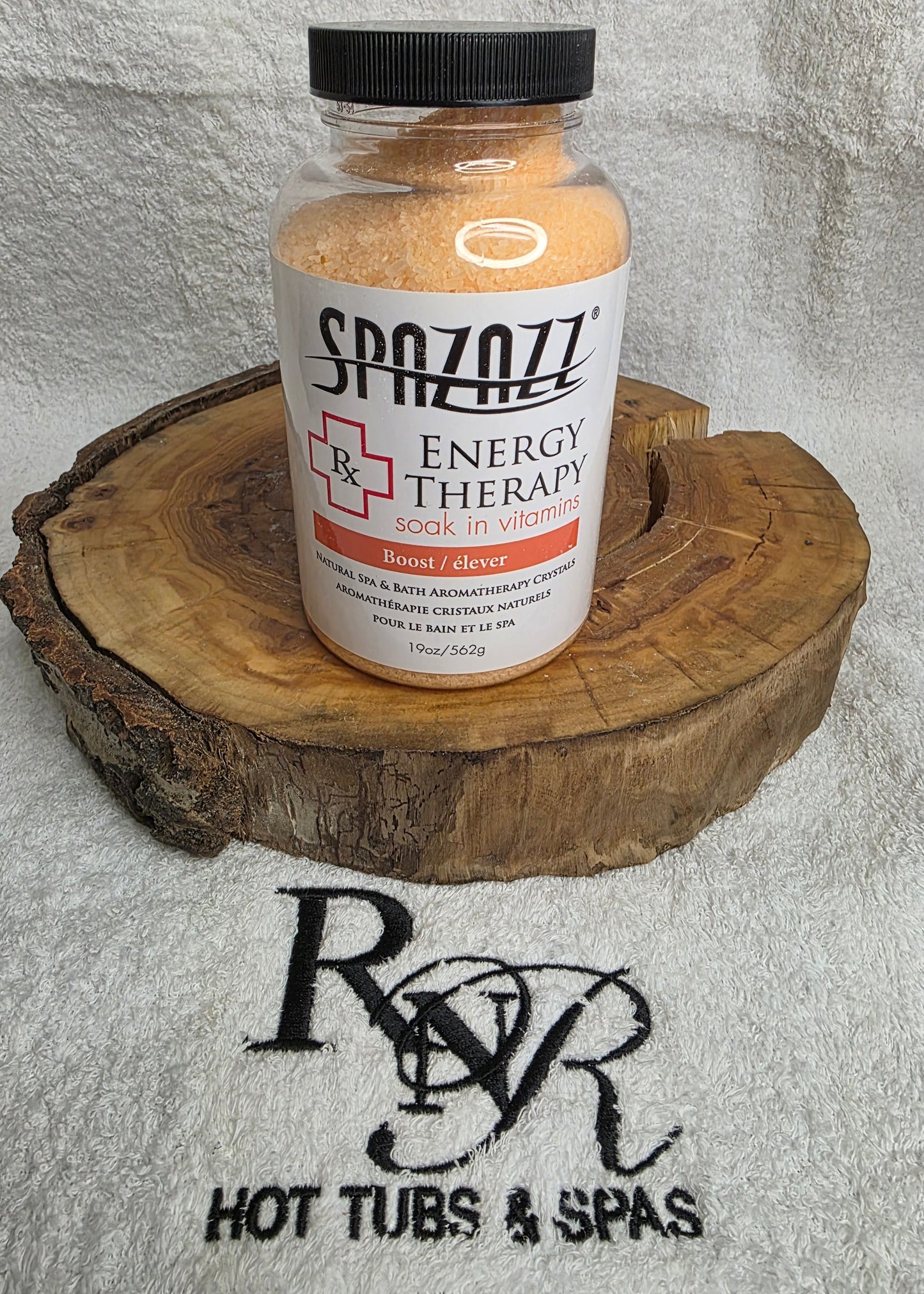 Bottle of Spazazz Energy Therapy aromatherapy crystals on a wooden block with a towel featuring RnR Hot Tubs & Spas logo in the background.