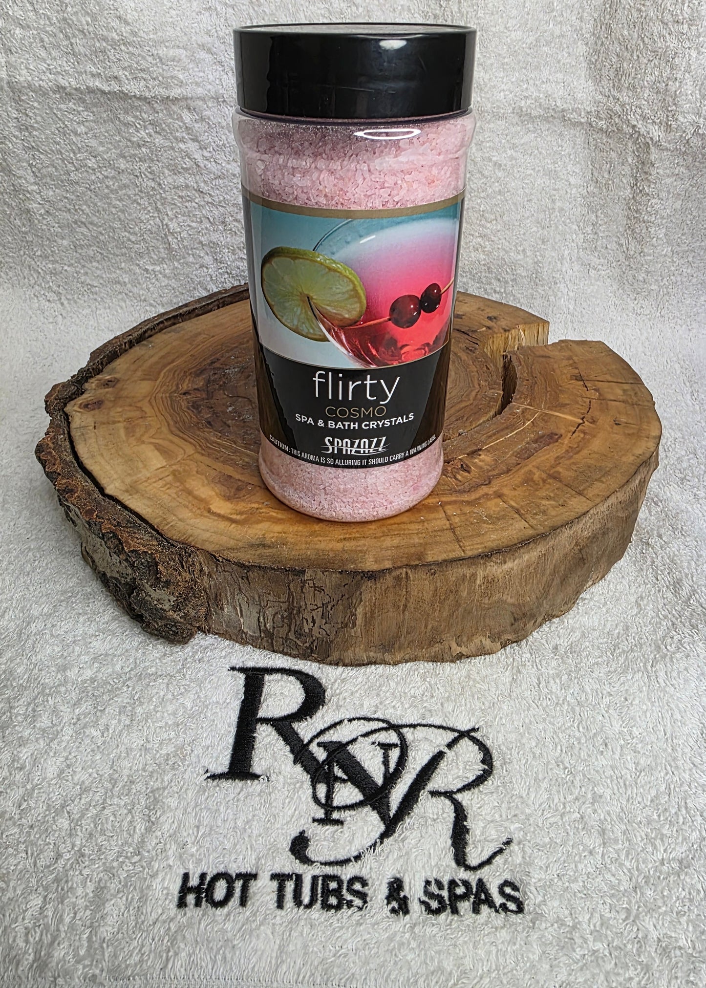 Bottle of Flirty Aromatherapy Crystals on a wooden block with RnR Hot Tubs & Spas branding in the background.