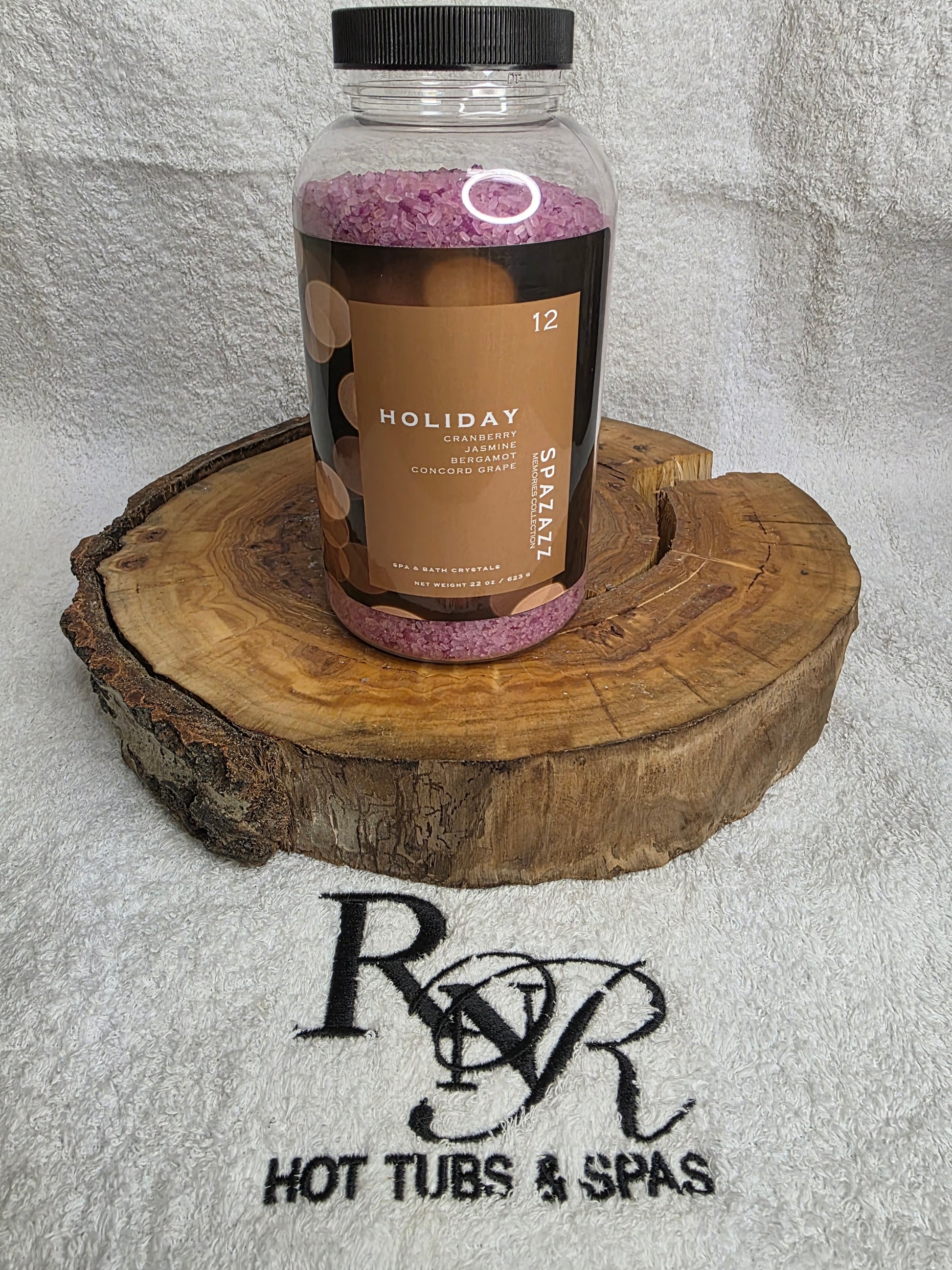 SpaZZZ Holiday bottle on a wooden block with RnR Hot Tubs & Spas logo in the background