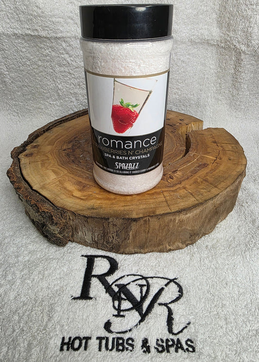 Bottle of Spazazz Romance aromatherapy crystals on a wooden block with RnR Hot Tubs & Spas logo in the background.