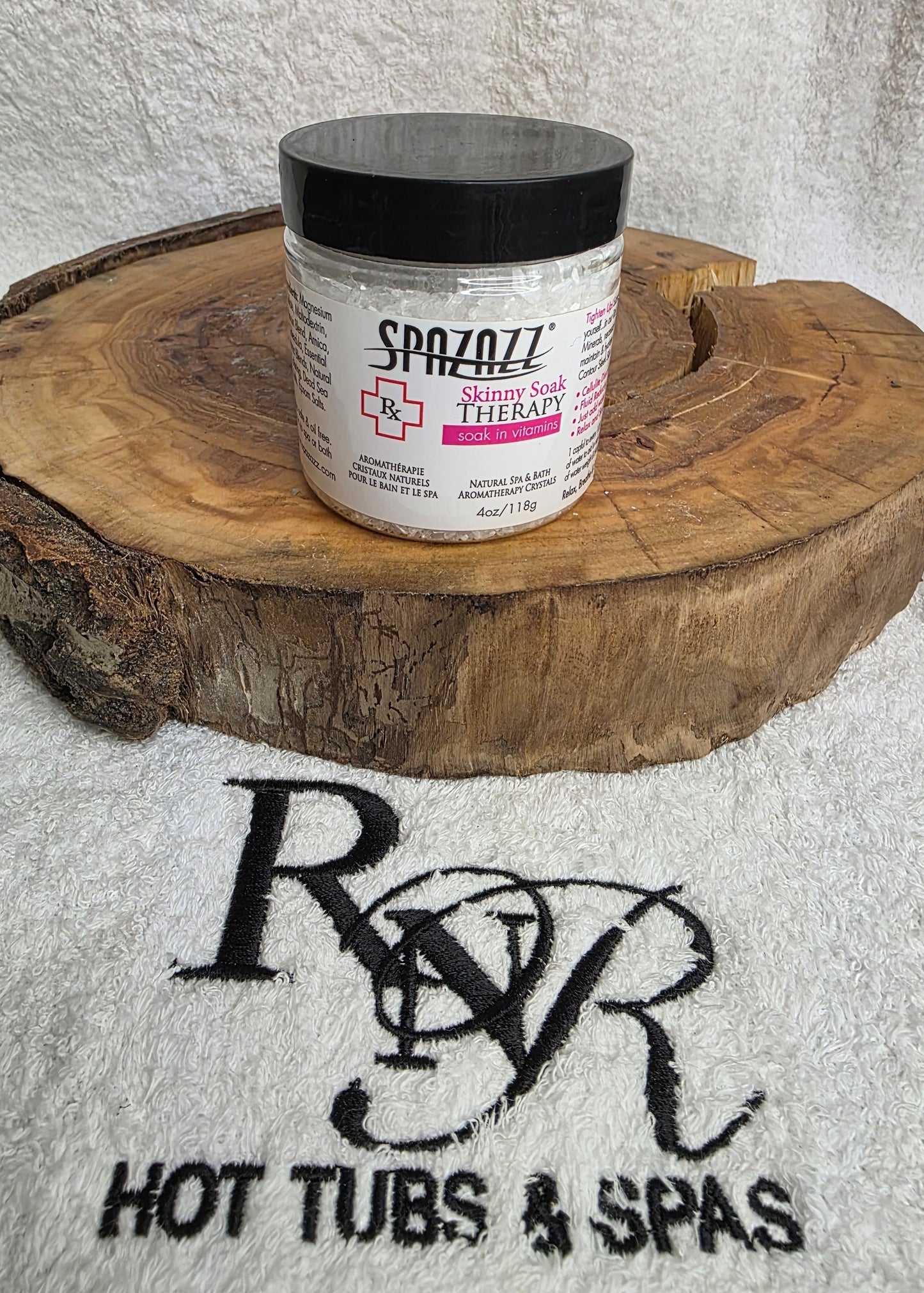 Small container of Spazazz Skinny Soak aromatherapy crystals on a wooden block with RnR Hot Tubs and Spas logo in the background.