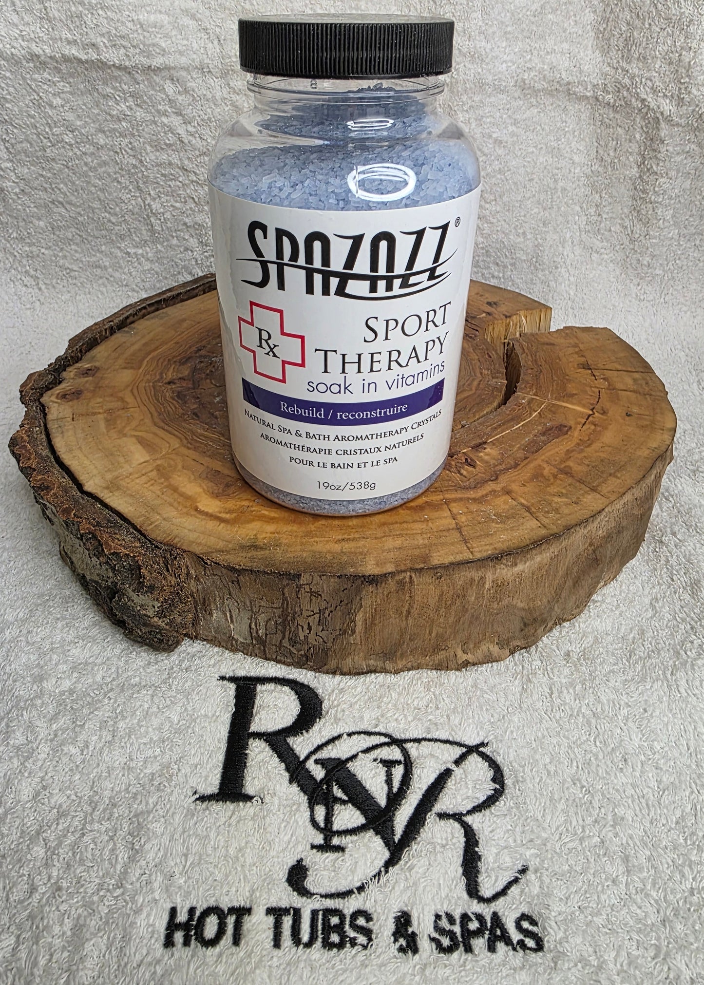 Bottle of Spazazz Sport Therapy aromatherapy crystals on a wooden block with RnR Hot Tubs & Spas logo in the background